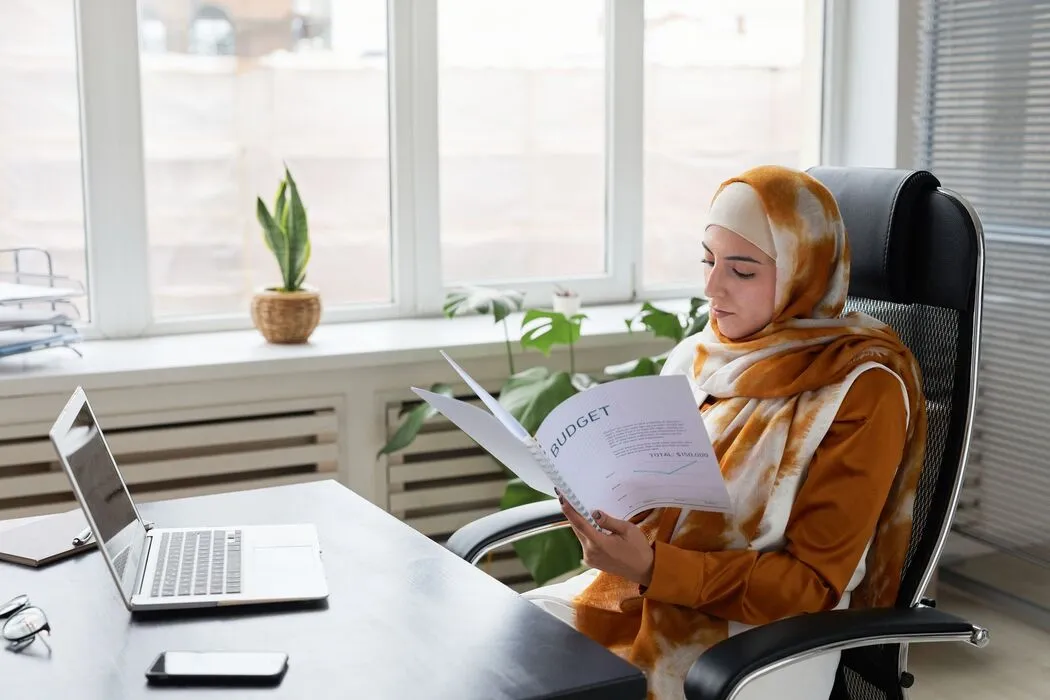 Business manager reviewing budget and invoice documents on a laptop